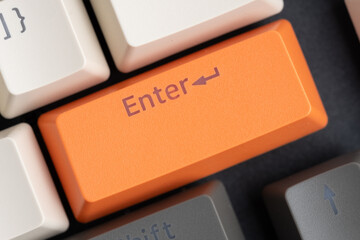 Orange key with word enter on computer keyboard. Closeup.