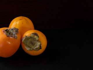 Oriental persimmon fruit, whole on a dark background, of the strong 