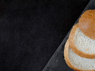 Sliced ​​slices of wheat bread on a dark stone slab.
