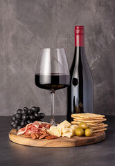 Food photography of red wine, cheese parmesan, prosciutto, olives, pecan, grapes, crackers, wine glass and bottle, assortment, party meal, snacks
