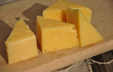 pieces of hard cheese on a wooden cutting board. selective focus