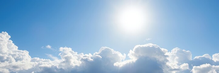 A bright sun shining through a blanket of fluffy white clouds in a clear blue sky, weather