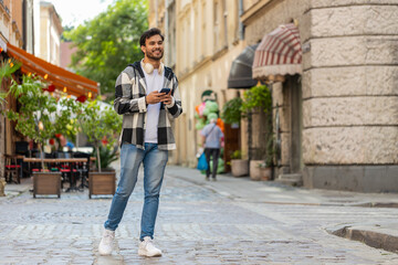Tourist traveler young man using smartphone typing text messages looking for search a way on map in...