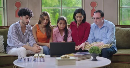 Indian family group mom dad son teen girl child watch film horror scene movie feel fear spend day time house Young adult man women sitting cozy sofa couch use laptop look screen have fun joy enjoy  - Powered by Adobe