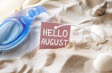 Welcome August text message decoration with seashell on beach background