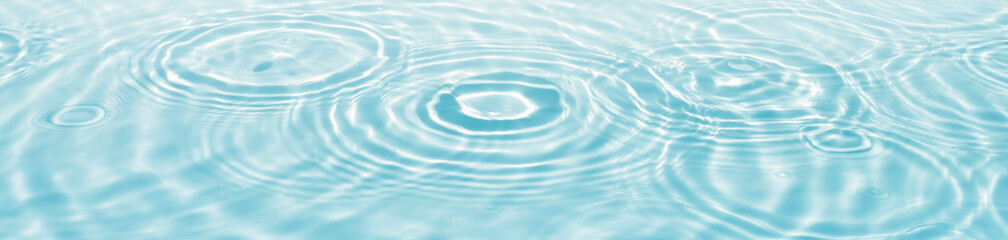 blue water surface with drop circles and sunlight reflections, empty fresh water texture banner background with copy space for beauty spa, travel or cosmetics