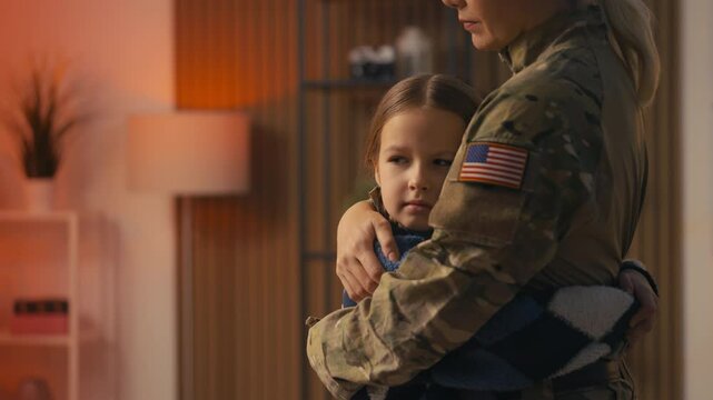 Sad little girl hugs her American military mom before she leaves for deployment