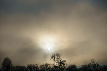 Beautiful sunset in warm colors, afternoon and evening mood in winter season with fog, sun behind...
