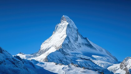 A mountain peak covered in snow under a clear sky, sharp and striking natural beauty