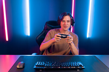 Enjoy smart gaming streamer with control joystick, playing game online of live streaming social media group with team skilled players on computer at modern technology cyber neon light room. Pecuniary.