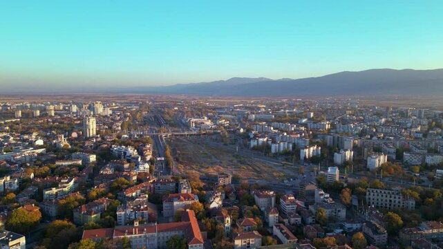 Aerial drone footage of a sunset over the city of Plovdiv in Bulgaria. Ancient city of Filipopolis filmed from above on a warm autumn afternoon. European city seen from a helicopter establishing shot.