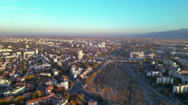 Aerial drone footage of a sunset over the city of Plovdiv in Bulgaria. Ancient city of Filipopolis filmed from above on a warm autumn afternoon. European city seen from a helicopter establishing shot.