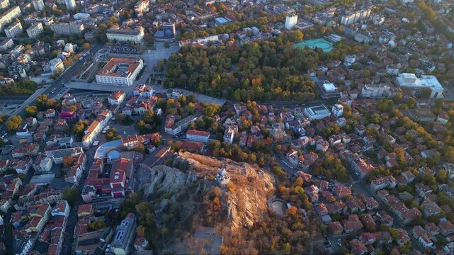 Aerial drone footage of a sunset over the city of Plovdiv in Bulgaria. Ancient city of Filipopolis filmed from above on a warm autumn afternoon. European city seen from a helicopter establishing shot.