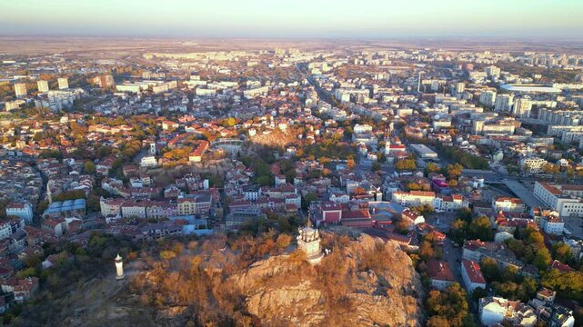Aerial drone footage of a sunset over the city of Plovdiv in Bulgaria. Ancient city of Filipopolis filmed from above on a warm autumn afternoon. European city seen from a helicopter establishing shot.