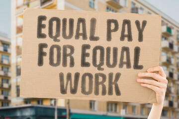 The phrase 'Equal pay for equal work' displayed on a banner held by a person. Workplace equity....