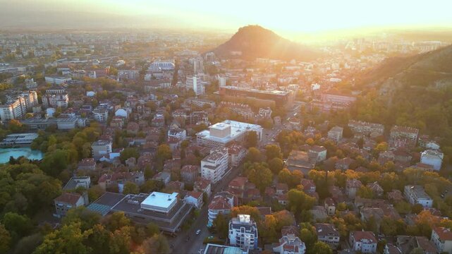 Aerial drone footage of a sunset over the city of Plovdiv in Bulgaria. Ancient city of Filipopolis filmed from above on a warm autumn afternoon. European city seen from a helicopter establishing shot.