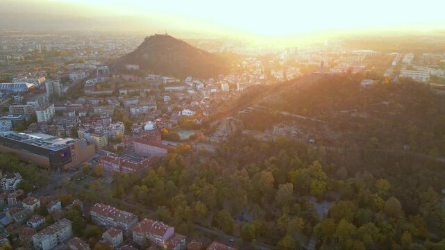 Aerial drone footage of a sunset over the city of Plovdiv in Bulgaria. Ancient city of Filipopolis filmed from above on a warm autumn afternoon. European city seen from a helicopter establishing shot.