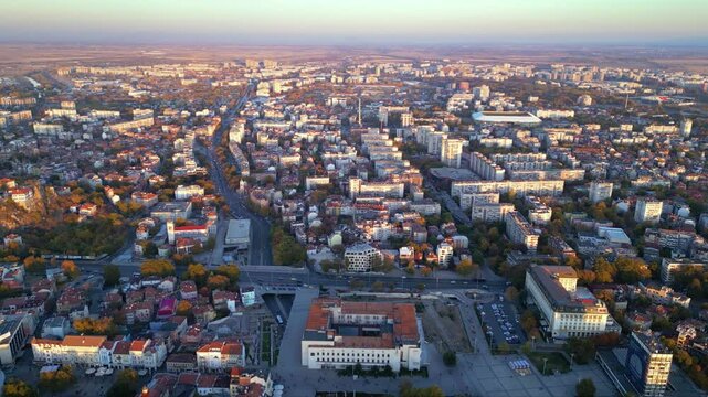 Aerial drone footage of a sunset over the city of Plovdiv in Bulgaria. Ancient city of Filipopolis filmed from above on a warm autumn afternoon. European city seen from a helicopter establishing shot.