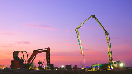 Construction workers group with concrete pump truck are working overtime while pouring concrete...