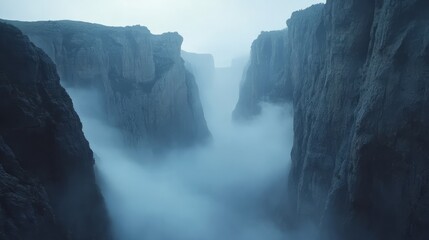 A misty canyon landscape at dawn, with fog rolling through the valley between towering cliffs