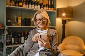 woman entrepreneur use cellphone drink coffee while sit in an armchair