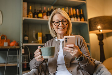woman entrepreneur use cellphone drink coffee while sit in an armchair