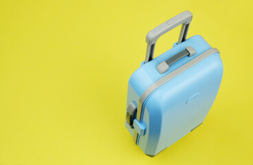 Blue travel suitcase on yellow background. Copy space for text.