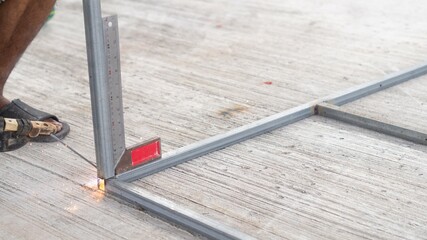 Worker welding perpendicular steel After using the protractor to measure degrees While erecting the...