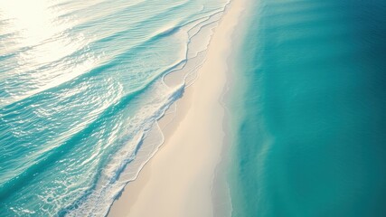 An aerial view of the turquoise ocean meeting a pristine white sand beach, the gentle waves creating a soft, mesmerizing contrast.