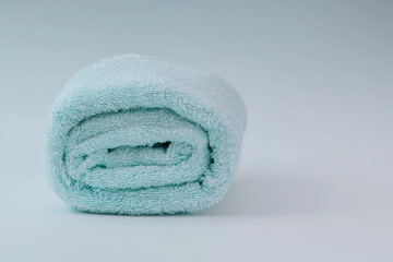 Soft mint green towel neatly rolled on a light background