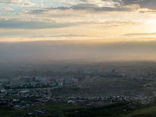 Drone view of clouds at sunset. Beautiful clouds in the sky, haze covered the town. Summer evening landscape.
