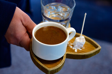 Turkish Coffee with Delight and Water. Close-up of Turkish coffee served with a glass of water and Turkish delight on a wooden tray, perfect for cafes.

