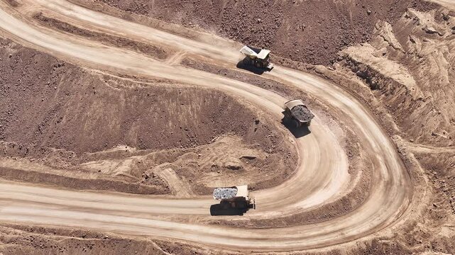 Loaded Mining Trucks Advancing Through an Open-Pit Copper Mine in Chile - High-Tonnage Mineral Transportation in a Rugged Mining Landscape