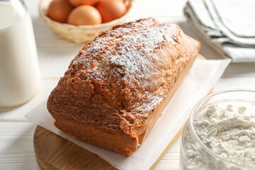 Tasty sponge cake with ingredients on white table, closeup