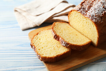 Freshly baked sponge cake on light blue wooden table, closeup