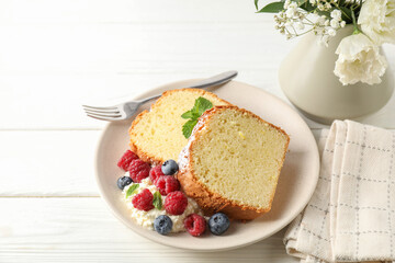Freshly baked sponge cake, whipped cream, berries and mint on white wooden table