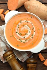 Delicious sweet potato soup with microgreens and fresh vegetables on wooden table, flat lay