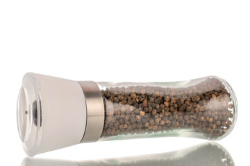 Black peppercorns in a glass grinder, macro, isolated on a white background.