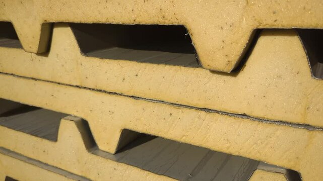 Sandwich panels are used for cladding walls and roofing, consisting of two metal sheets with an insulating core. They are stacked in storage after production.
