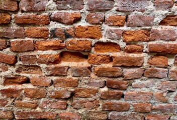 The old red brick wall with the white cement to cover around the brick. and the wall brick damage