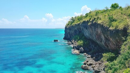 Lush green cliff overlooking vibrant turquoise ocean.