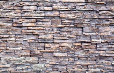 Grayish brown stone external wall covering wall made of irregular bricks of natural rocks.  Background and texture.