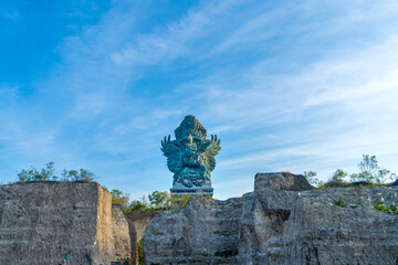 The Garuda Wisnu Kencana (GWK) statue a monumental landmark, standing 121 meters tall in the Garuda Wisnu Kencana Cultural Park, Bali, looks majestic from the gap in the rock cliff.