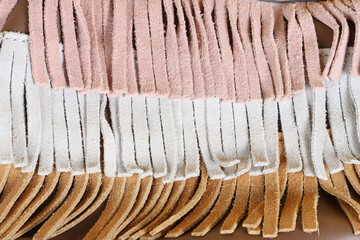 A close-up of fringe fabric texture in different colors, showcasing the soft suede material and...