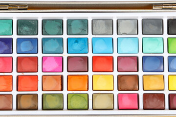 background of a watercolor paint palette, showcasing the vibrant colors and intricate details of the paint wells
