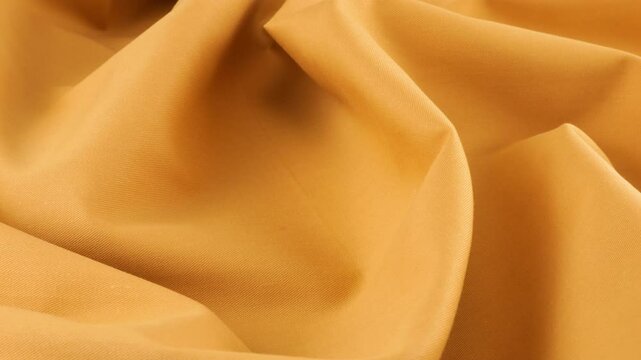 Top view of the soft folds of topaz orange cotton fabric rotated on the display case. Textile background on the design theme, craft, handmade, patchwork, creativity theme.