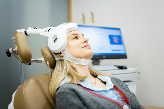 A Caucasian girl in her 20s or 30s undergoes transcranial magnetic stimulation therapy at a psychiatric facility to treat depression or anxiety.
