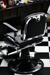 Classic barber chair in a retro style barbershop with black and white flooring