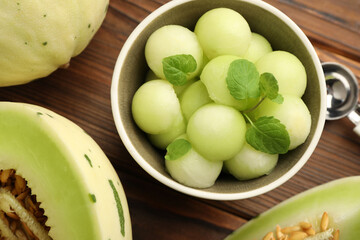 Melon balls in bowl and fresh fruit on wooden table, flat lay