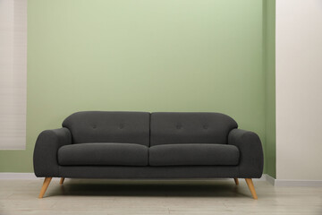 One stylish sofa near green wall indoors